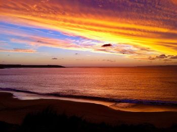 Scenic view of sea against dramatic sky during sunset