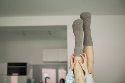 Low section of woman wearing socks with feet up at home