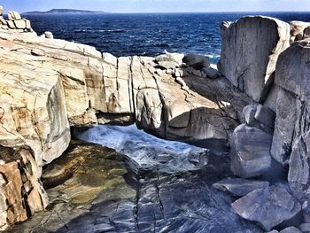 Rock formation in sea against sky