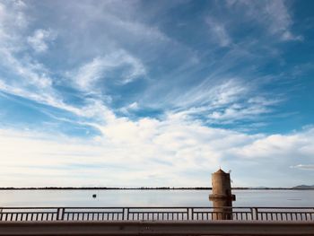 Bridge over sea against cloudy sky