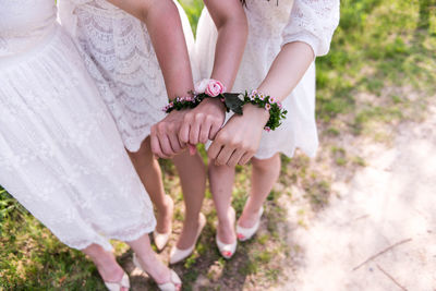Low section of bridesmaid with flower bracelets