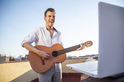 Handsome young singer performing for his fans on social media from the roof of his house during quarantine