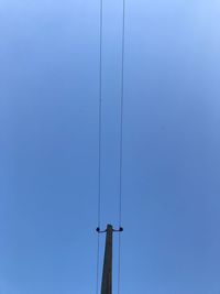 Low angle view of telephone pole against clear blue sky