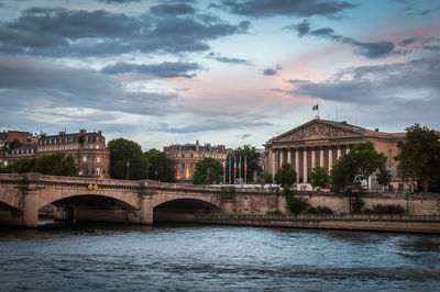 Arch bridge over river against buildings in city