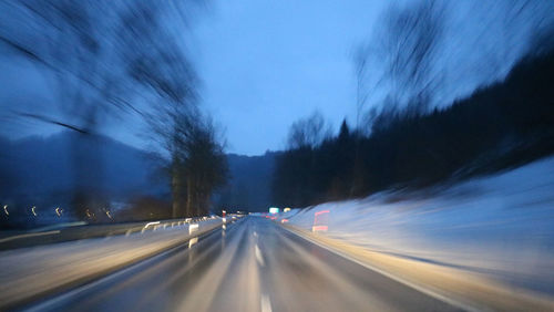 Light trails on road against sky