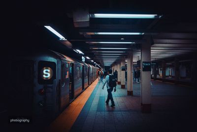 Rear view of man walking at illuminated railroad station