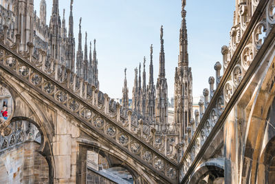 View to spires and statues on roof of duomo through ornate marble fencing. milan, italy