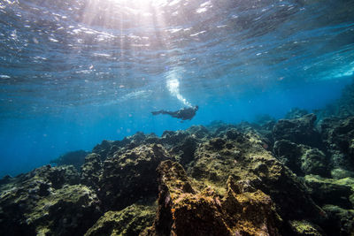 Person in sea against blue sky