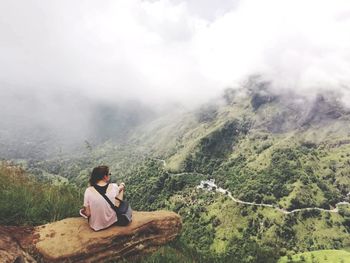 Woman sitting on rock at mountain