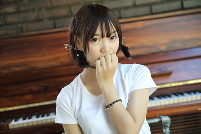 Portrait of beautiful young woman sitting against piano