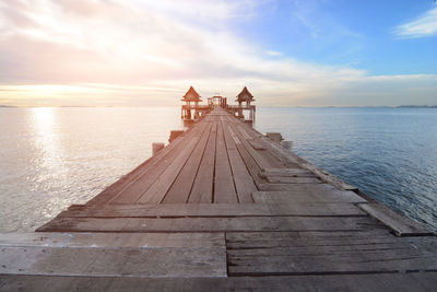 Pier over sea against sky during sunset