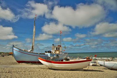 Sailboats moored on beach against sky