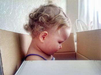 Portrait of cute girl in box at home