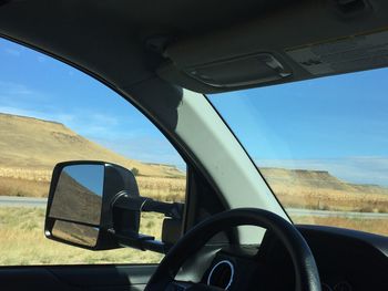 Vehicles on country road against blue sky