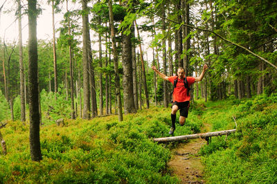 Man standing on tree trunk in forest