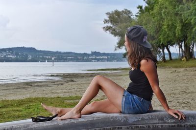 Woman sitting at beach against sky