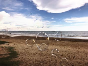 Bubbles flying over beach against sky