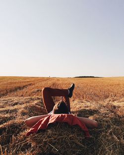 Woman sitting on field against clear sky