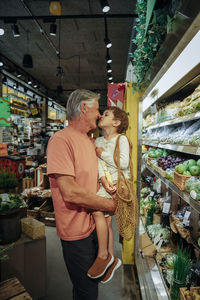 Grandfather and grandson rubbing noses while standing by vegetable section in supermarket