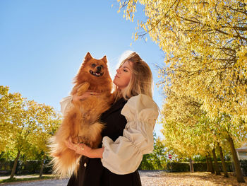 Woman with dog against sky during autumn