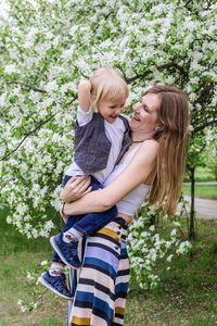 Young smiling mother with son in apple tree garden. 