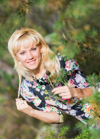 Portrait of beautiful woman holding pine leaves at forest