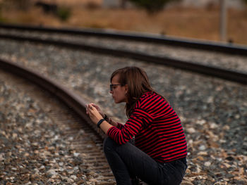 Girl sitting on railroad track
