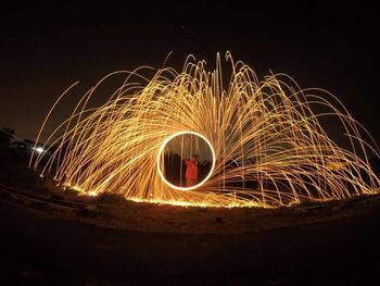 Man spinning wire wool on field at night