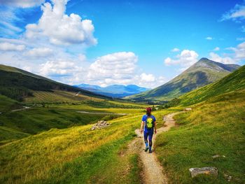 Rear view of man walking on mountain against sky