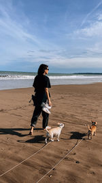 Rear view of woman standing on beach against sky