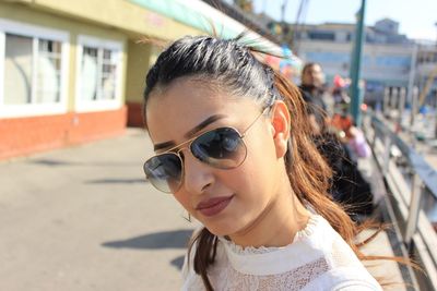 Close-up of confident beautiful woman wearing sunglasses on footpath