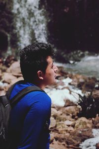 Side view of backpacker by waterfall in forest