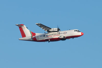 Low angle view of airplane flying against clear blue sky