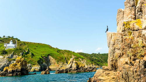 Scenic view of sea by mountain against clear sky