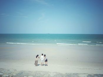 Rear view of women on beach against clear sky