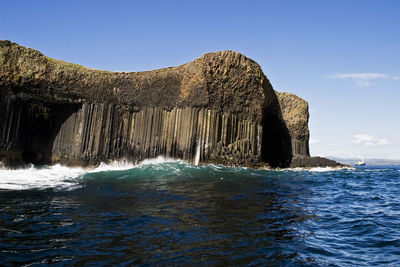 Rock formation in sea against blue sky