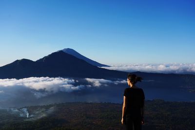 Rear view of man looking at mountains against sky