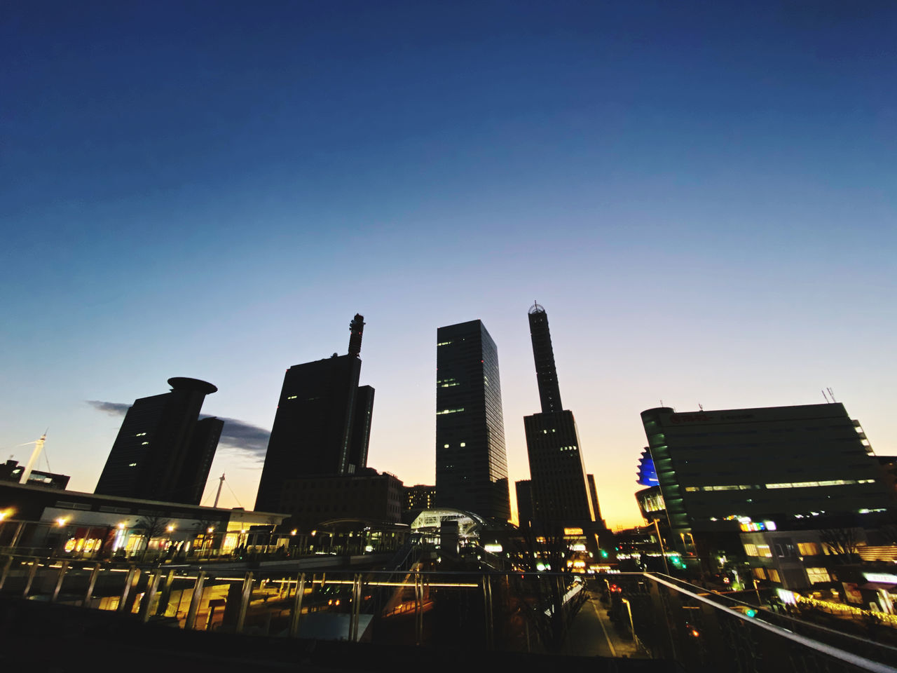 LOW ANGLE VIEW OF ILLUMINATED BUILDINGS AGAINST CLEAR SKY IN CITY