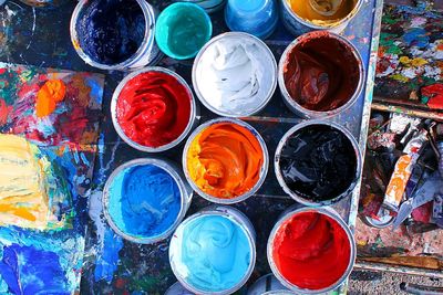 Directly above shot of multi colored painting cans on table