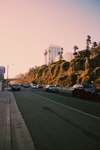 Cars on road against sky at sunset