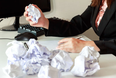 Midsection of man holding paper while sitting on table