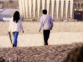 Rear view of people walking on street in city