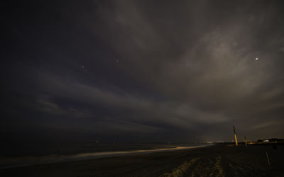 Road by sea against sky at night