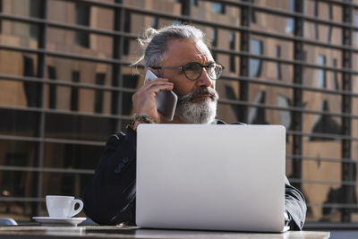 Man using mobile phone while sitting on table