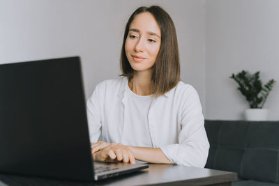 Portrait of a smiling young woman using phone