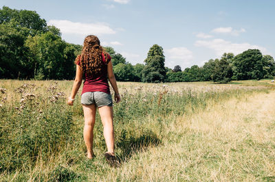 Rear view full length of woman standing on grassy field