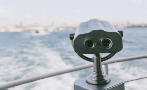 Coin-operated binocular on boat sailing in sea against sky