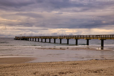 Pier over sea against sky during sunset