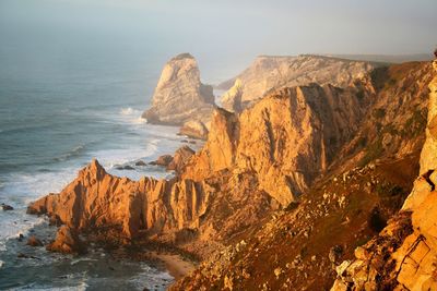 Scenic view of rock formations in sea against sky