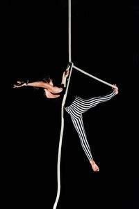 Woman rope climbing against black background